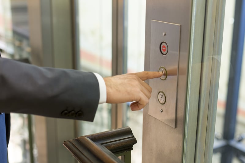 Business man pressing button for elevator.