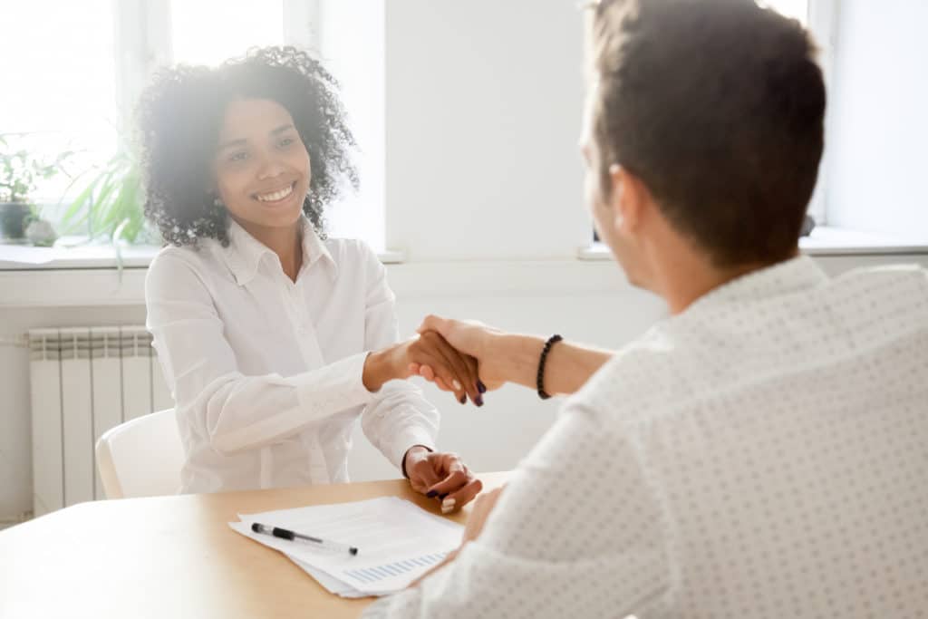 Man and woman shaking hands after successful salary negotiations.