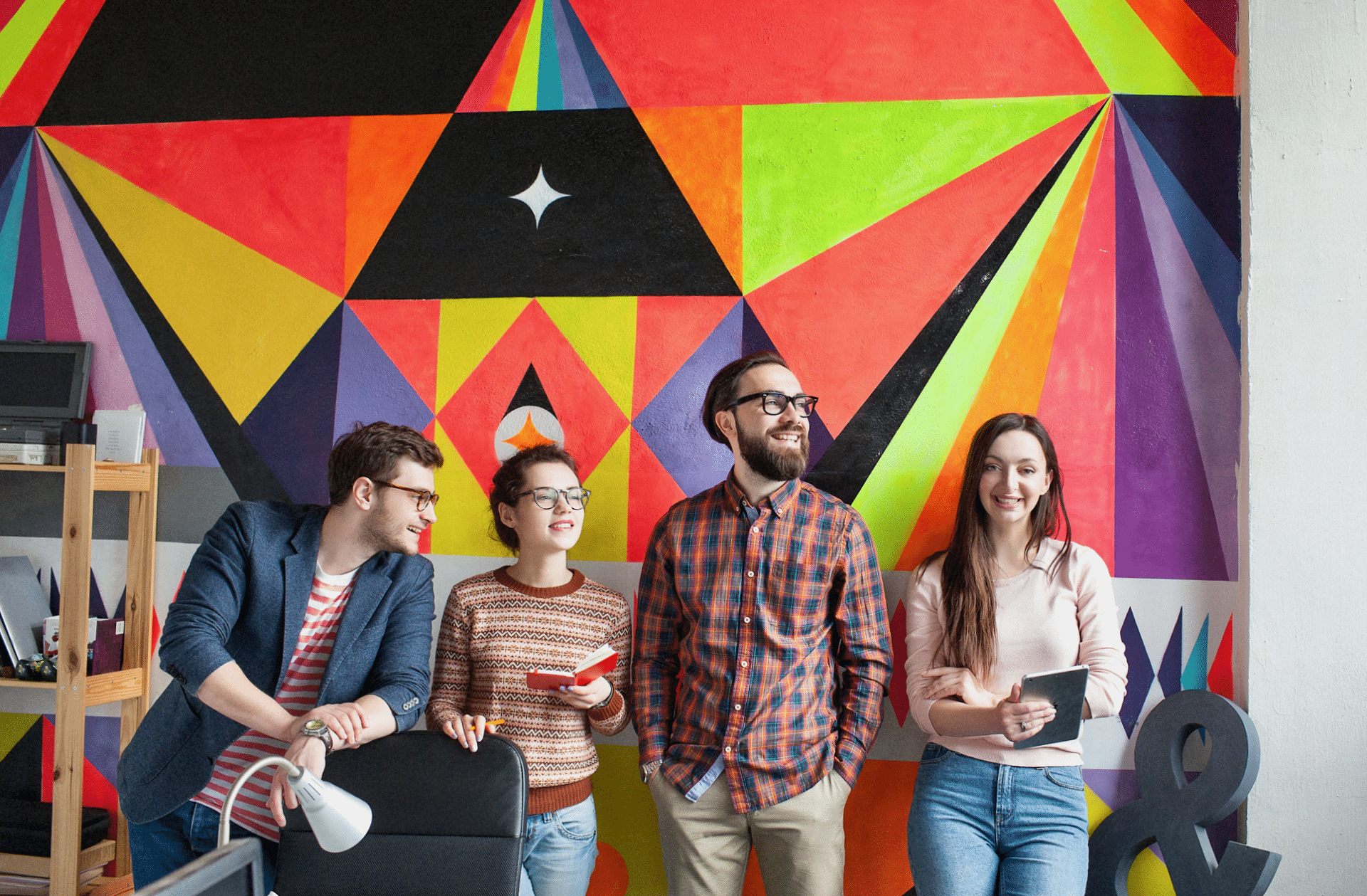Agency team of men and women in front of a creative-colored wall.