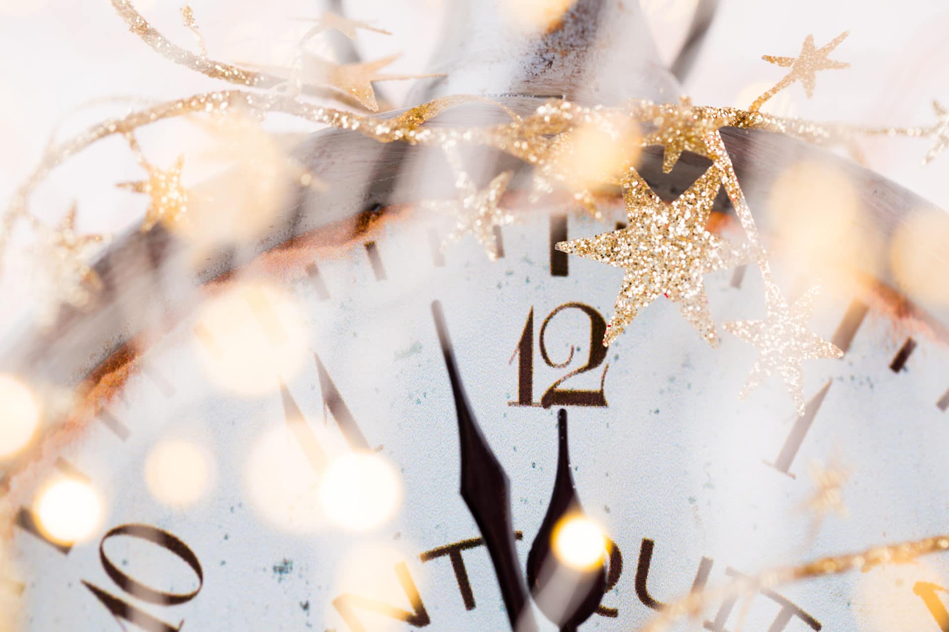 White clock surrounded by gold tinsel about to strike midnight