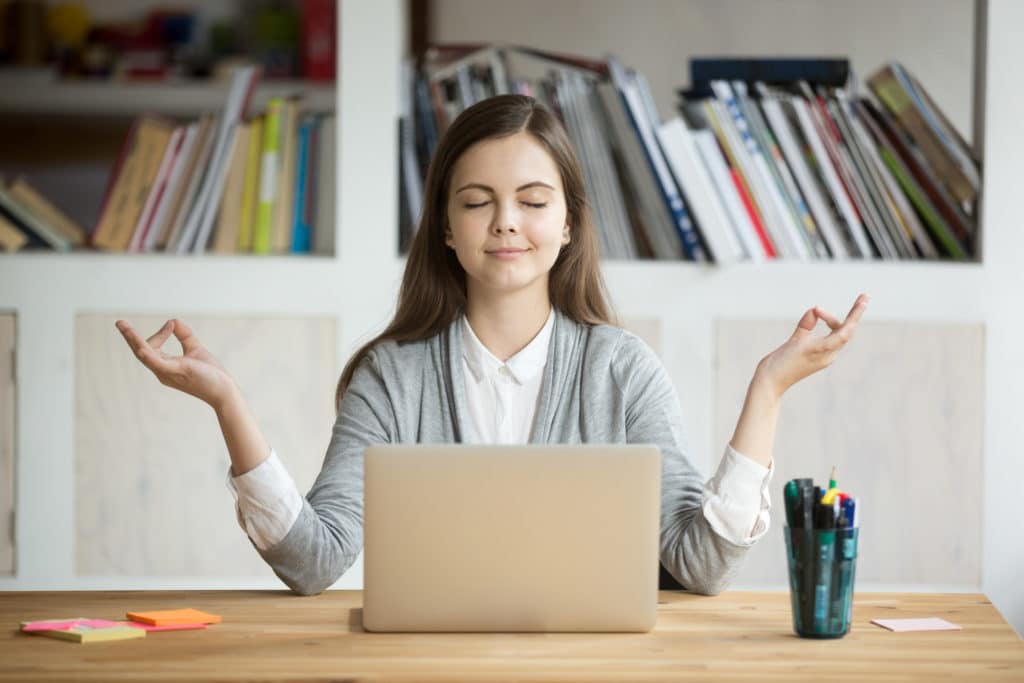 Woman meditating and being mindful at her desk at work