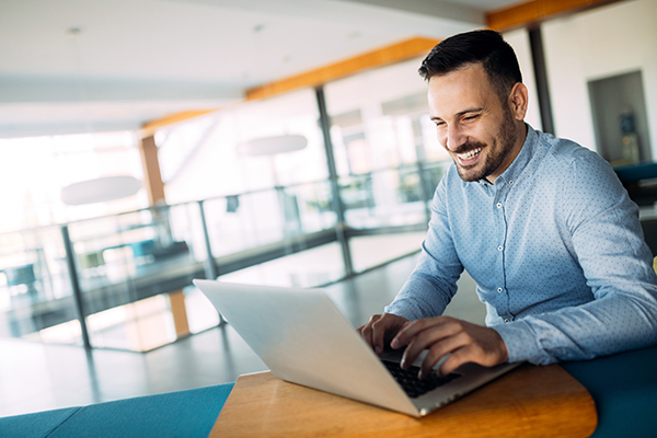 Young handsome employee working on computer during working day in office